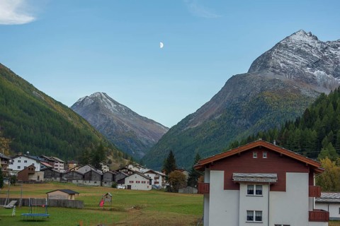 A mountain village with scattered houses in a valley between high mountains under a clear sky with