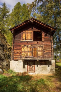 Old wooden house in rustic style in sunny autumn weather in the Alps. Surrounded by trees and green