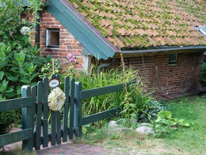 A small brick house with a moss-covered roof and a garden fence, Spiekeroog, East Frisia, GERMANY