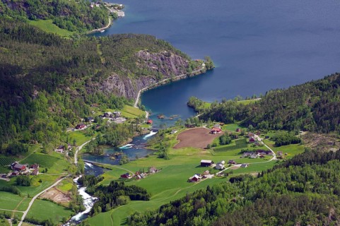 Rural landscape with a village by a lake, surrounded by hills and forests, Lovatnet, Loen,