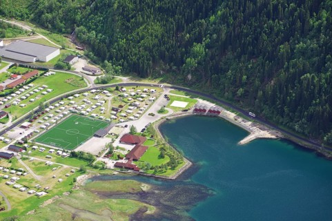 Top view of a campsite with football pitch and neighbouring lake in the middle of a forest, view