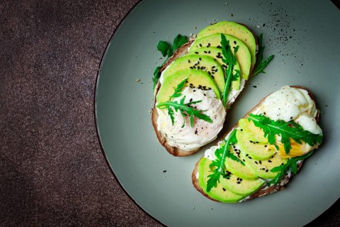 Sandwich with cream cheese, sliced avocado and boiled egg, arugula, on grainy bread, homemade,