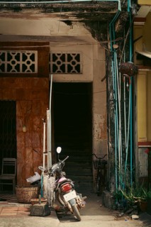 An old, weathered building entrance with a motorbike parked in front exuding a rustic and urban