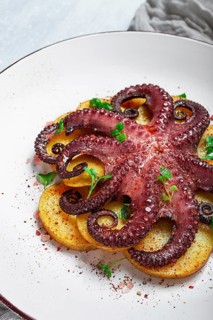 Octopus with potatoes and spices, on a light plate, top view, no people, homemade, close-up