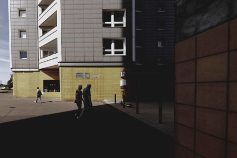 Two elderly people are silhouetted in front of a block of flats in Marzahn, taken in Berlin,
