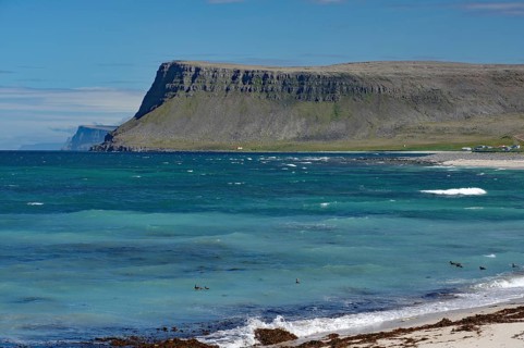 A vast sea with imposing cliffs and blue water, surrounded by a green coastline, Latrabjarg,