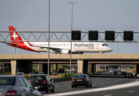 Amsterdam Schiphol Airport, Helvetic Airways Embraer ERJ-195, aircraft on the taxiway, bridge over