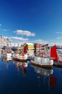 Fishing boats with red sails lying calmly on the quay, reflected in the water, surrounded by