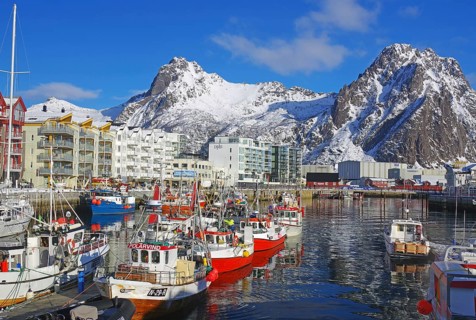 Colourful boats in the harbour, surrounded by snow-covered mountains and a lively town, fishing,