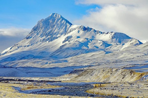 Imposing snow-covered mountain under a slightly cloudy blue sky, winter, Öxnadalur, Akureyri,