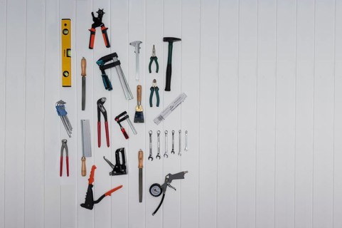 Tools on the wall, file, rasp, stapler, blind rivet pliers, spirit level, hammer, metre rule,