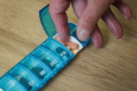An elderly man takes pills from a pill box. Berlin, 05.08.2024