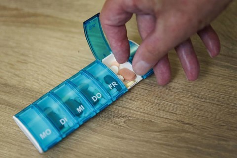 An elderly man takes pills from a pill box. Berlin, 05.08.2024