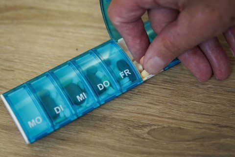 An elderly man takes pills from a pill box. Berlin, 05.08.2024
