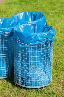 Rubbish bins with blue rubbish bags standing in a meadow, Germany, Europe