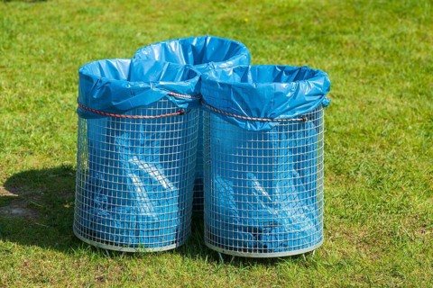 Rubbish bins with blue rubbish bags standing in a meadow, Germany, Europe