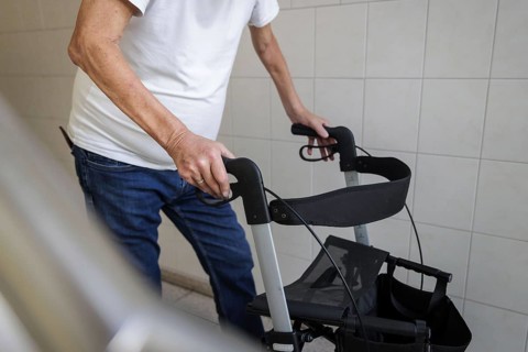 An elderly man walks with a rollator through a hallway in Berlin, 05/08/2024