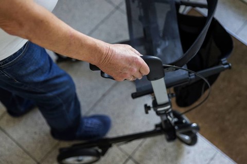 An elderly man walks with a rollator through a hallway in Berlin, 05/08/2024