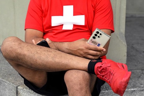 Man with mobile phones and Swiss cross