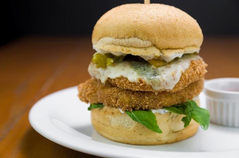 Close-up of homemade tasty chicken burger on wooden table and black background