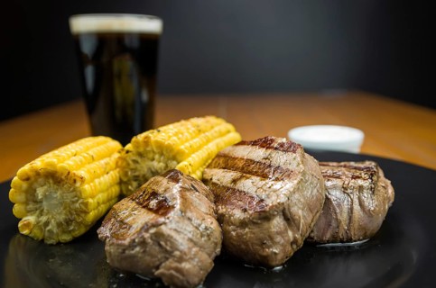 Delicious filet mignon close-up with roasted corn and glass of beer