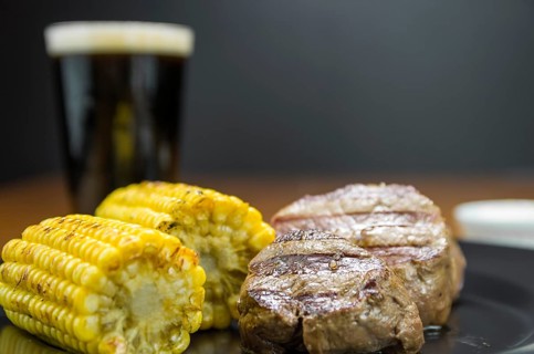 Delicious filet mignon close-up with roasted corn and glass of beer