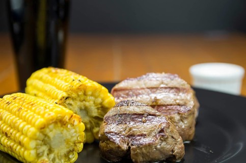 Delicious filet mignon close-up with roasted corn and glass of beer