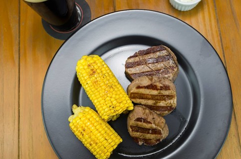 Delicious filet mignon close-up with roasted corn and glass of beer