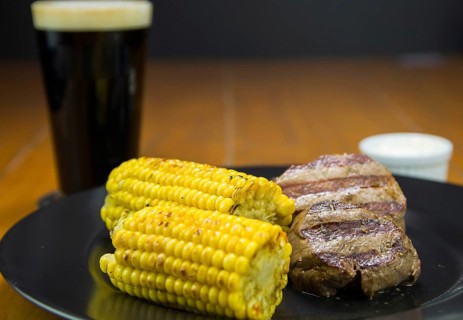 Delicious filet mignon close-up with roasted corn and glass of beer