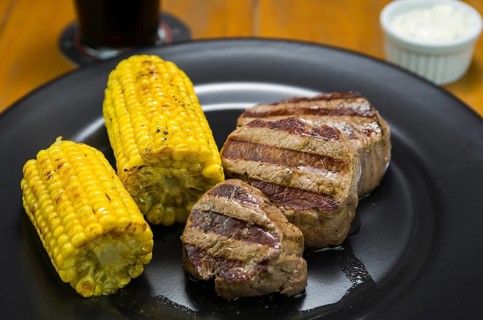 Delicious filet mignon close-up with roasted corn and glass of beer