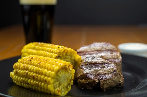 Delicious filet mignon close-up with roasted corn and glass of beer
