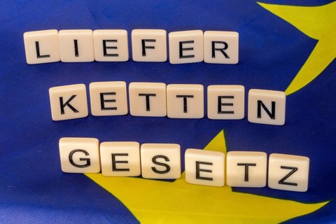 Letters on an EU flag show the word SUPPLY CHAIN LAW