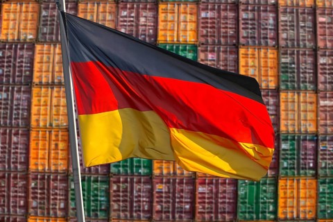 Symbolic image of the German economy: German flag in front of a large stack of shipping containers