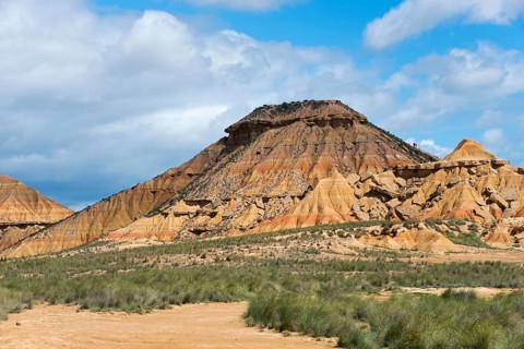 Rocky hill in an arid landscape under a blue sky with clouds, Bardenas Reales Natural Park, desert,