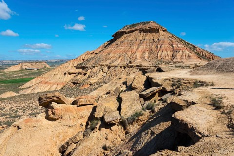 Stony hill in a desert-like landscape under a blue sky with few clouds, Bardenas Reales Natural