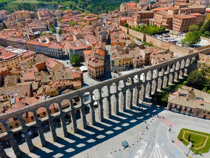 Aerial view of a historic aqueduct running through a town with mainly brick-roofed houses and a few