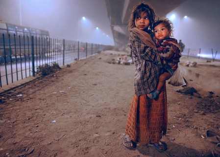 New Delhi, India, 21.01.2010, A homeless girl holds her sister in her arms. She and her family are