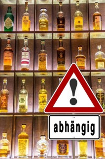 Shelf full of alcohol bottles with a warning sign about alcohol addiction, illuminated in a bar