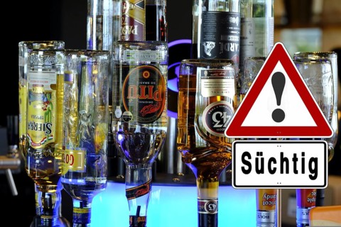 Alcohol bottles in a bar with a warning sign about the danger of addiction, illuminated with neon