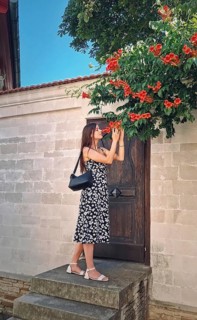 Young woman enjoys a beautiful summer day in vacation standing at the threshold of a door smelling