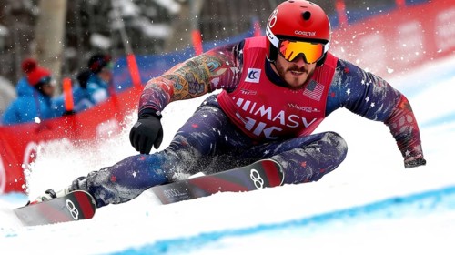 Snowboarder making a sharp turn during a race, with a focused expression and dynamic winter sport