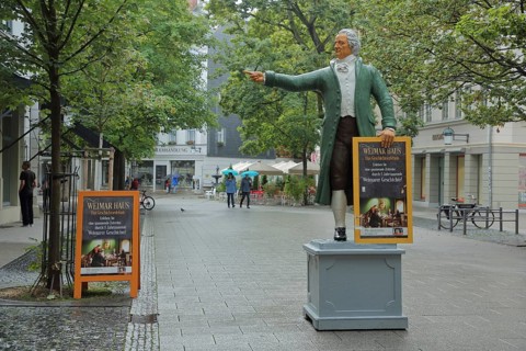 Sculpture of Johann Wolfgang von Goethe in historical clothing and poster signposting the way to