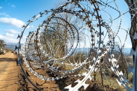 Spiral barbed wire installation beside a road in daylight, highlighting security and open