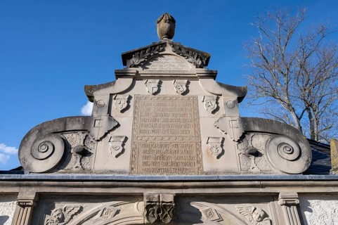 Detail of the entrance portal of the cemetery, since 1618, with volutes and coats of arms of the