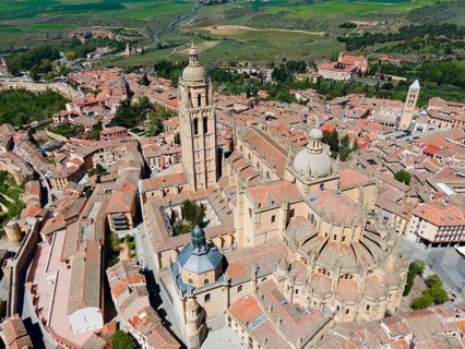 Panoramic view of a medieval city with a prominent church surrounded by green countryside and