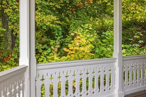 White wooden railing on a terrace with joinery and autumn colors in the forest