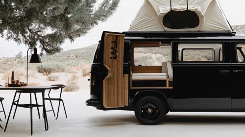 Black van with pop-up roof and open side door revealing a modern interior, parked near a dining
