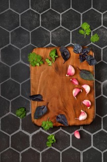 Overhead composition with place for text with wooden chopping board with basil, garlic and cilantro