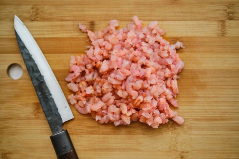 Overhead view of roughly chopped shrimps on cutting board