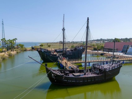 Resting harbour with historical replicas of sailing ships in the water under a clear sky, aerial